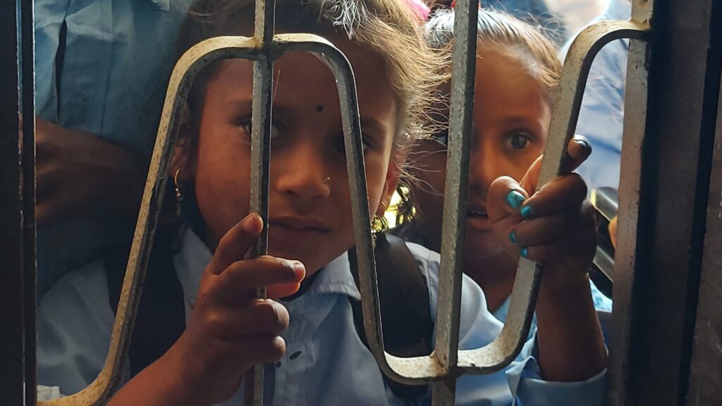 A curious girl looking through a classroom window